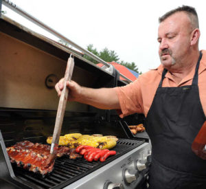 Ron Kyllonen, owner of Moose's Mobile Kitchen, brushes barbecue sauce on ribs in his backyard, where he was preparing a barbecue for an upcoming event recently. (RUSS DILLINGHAM/SUN JOURNAL)