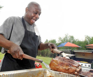 Ed Ford Sr. removes a perfectly cooked set of ribs from a pan at Moose's Mobile Kitchen. (RUSS DILLINGHAM/SUN JOURNAL)