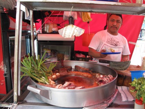 A taco chef stands behind a grill covered with grease and sizzling meat in Mexico City's Roma Norte neighborhood.(Nathaniel Parish Flannery) 
