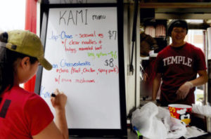 Kami Cart food truck owner and cook Jin Jang, left, writes out her menu as Ki Song, right, waits for the second annual Foodstruck event to begin in April. Korean and Asian trucks are a big draw at the events, the third of which is happening Sunday at Penn Park in York. (File — flipside)