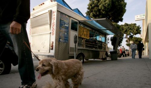 A man walks a dog past a taco truck parked on Venice Blvd. in Los Angeles May 2, 2008. The RAND Corporation partnered with a dozen Los Angeles-area food trucks to test whether healthier menu options would sell. DANNY MOLOSHOK/REUTERS