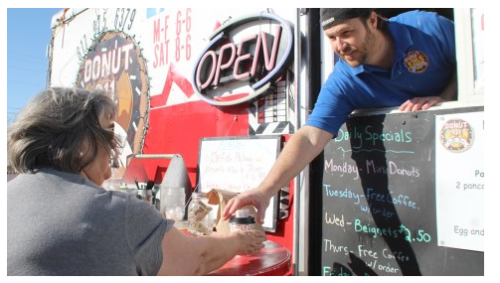 Brandon Alarcon passes along a coffee during the morning rush. 911 Donuts and Diner has been in its current location since January and has doubled its profits since they first started. (Photo by Paige Lambert)