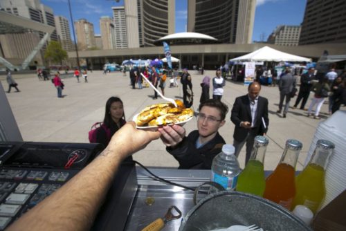 Victor Reinosso, owner of La Novela,  hands lunch to U of T student Brandon Renvina  on Wednesday outside city hall. There are currently  49 permitted mobile food trucks in Toronto.   (CHRIS SO / TORONTO STAR) |