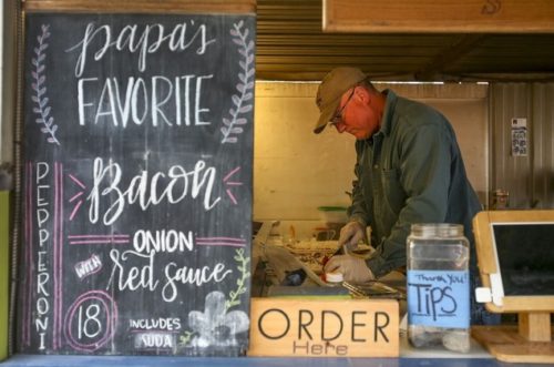 Kevin Clark / The Herald Norm Thomson prepares a pizza of the wood-fired oven  at his truck in Machias on May 22. Thomson and  other food truck vendors will soon move to a parking area on the Centennial Trail.